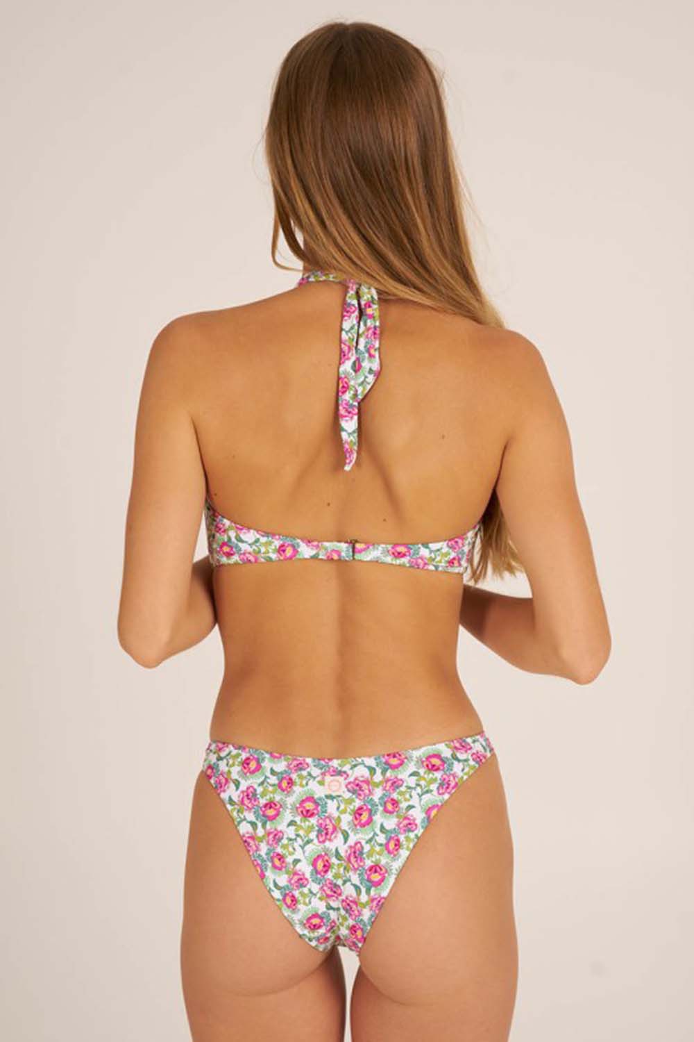modelo de espalda con bikini con estampado floral en color fucsia y verde y slip de corte semi brasileño cierre regulable en la espalda y nudo en el cuello