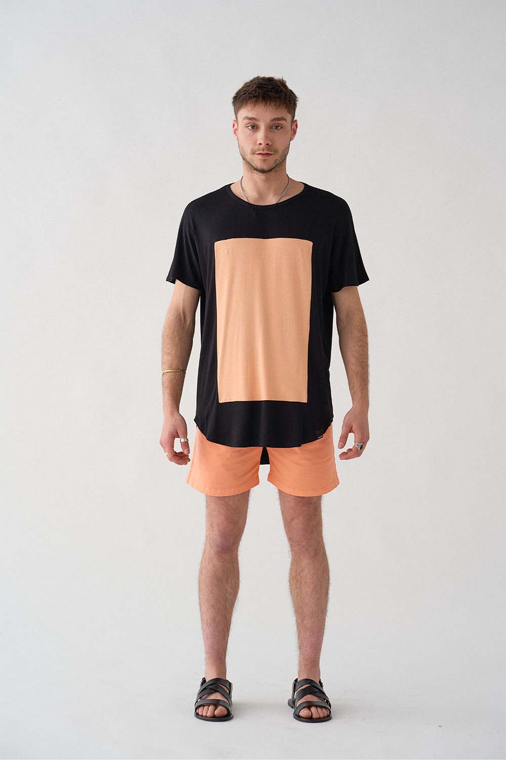 imagen entera del modelo con camiseta quadrilaterus negro y salmón y shorts salmón