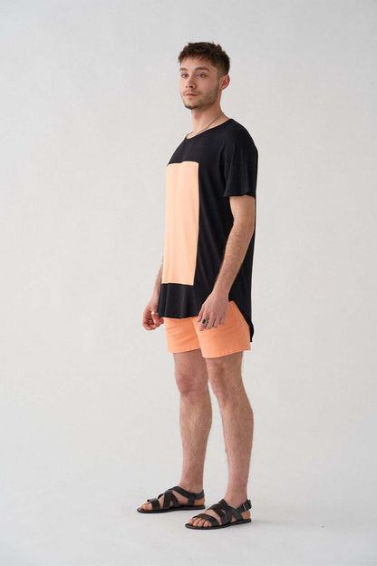 imagen de lado del modelo con camiseta quadrilaterus negro y salmón y shorts salmón