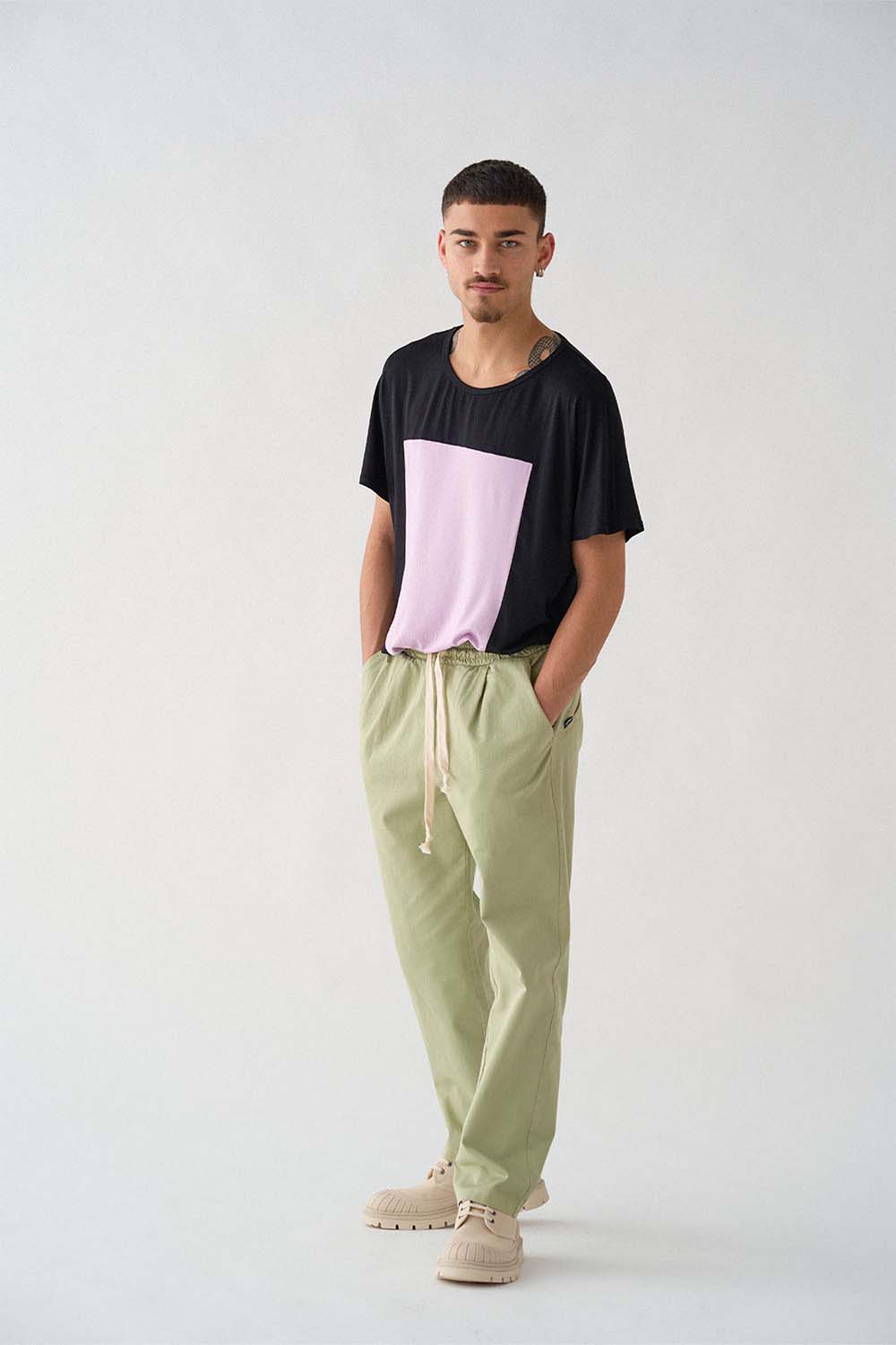 imagen de lado del modela con camiseta quadrilaterus negro y lila y pantalón worker verde