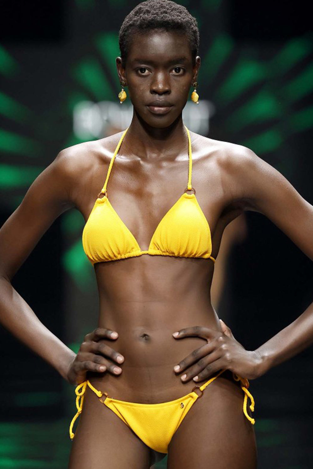 chica en desfile con bikini amarillo con tiras aros y nudos laterales a la braga